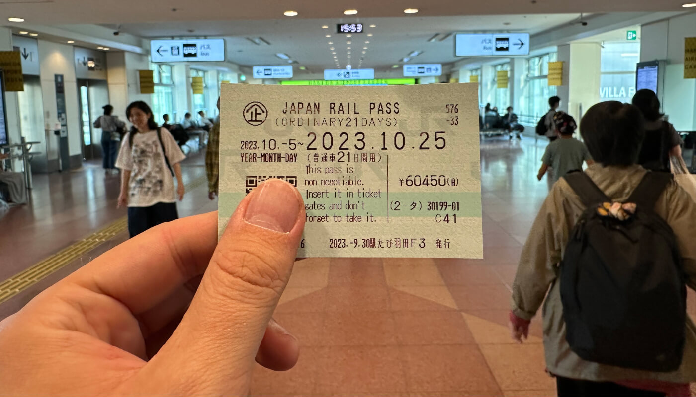 Min hand som håller i den lilla biljetten för Japan Rail Pass.