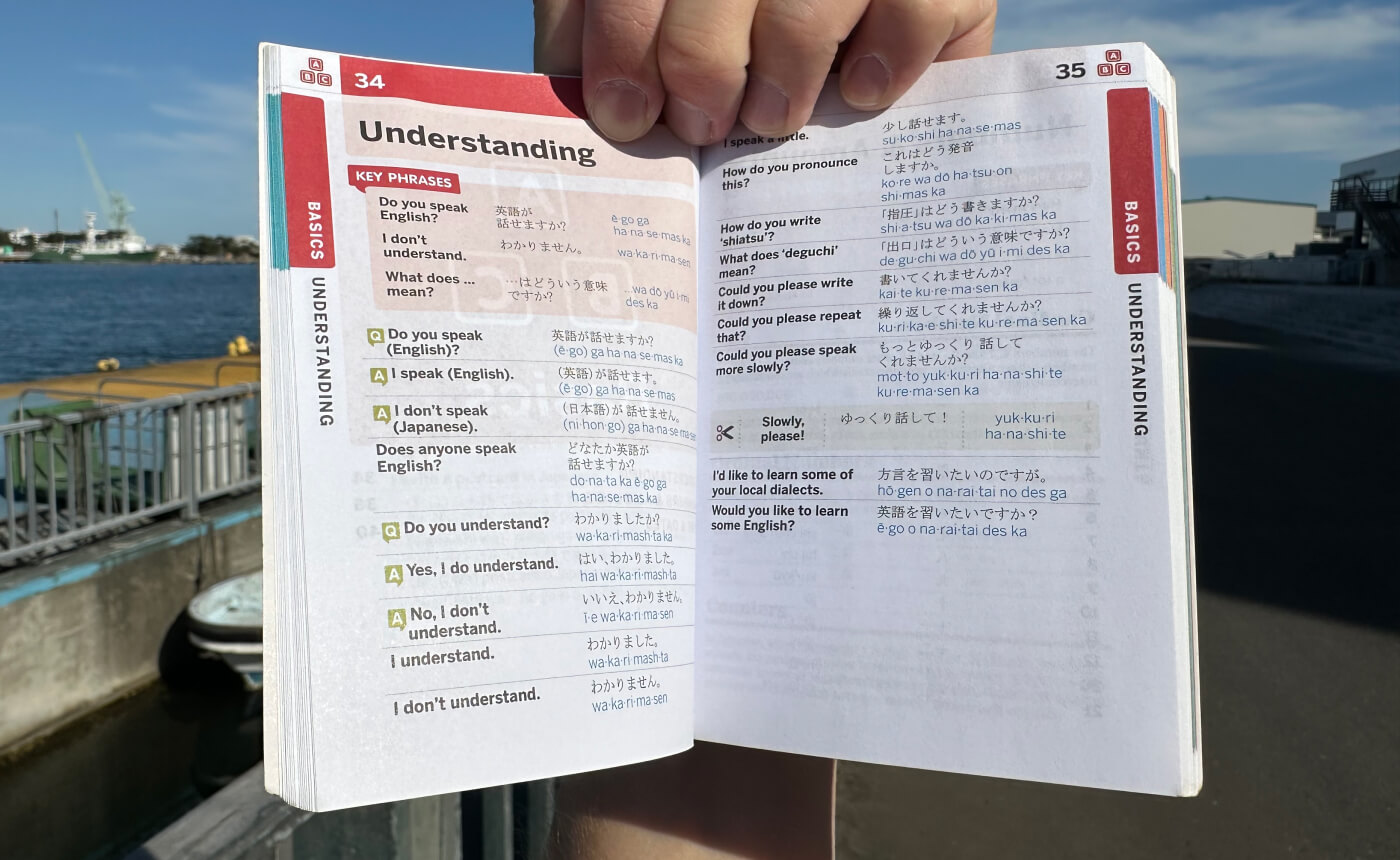 Hand håller i en liten bok. Två sidor syns. Innehållet handlar om enkla fraser för att förklara om man förstår något eller inte.