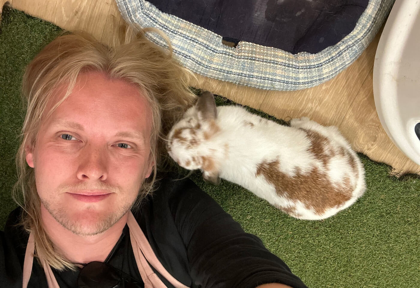 Selfie på mig liggande på golvet. En kanin är väldigt nära mott vänstra ö.