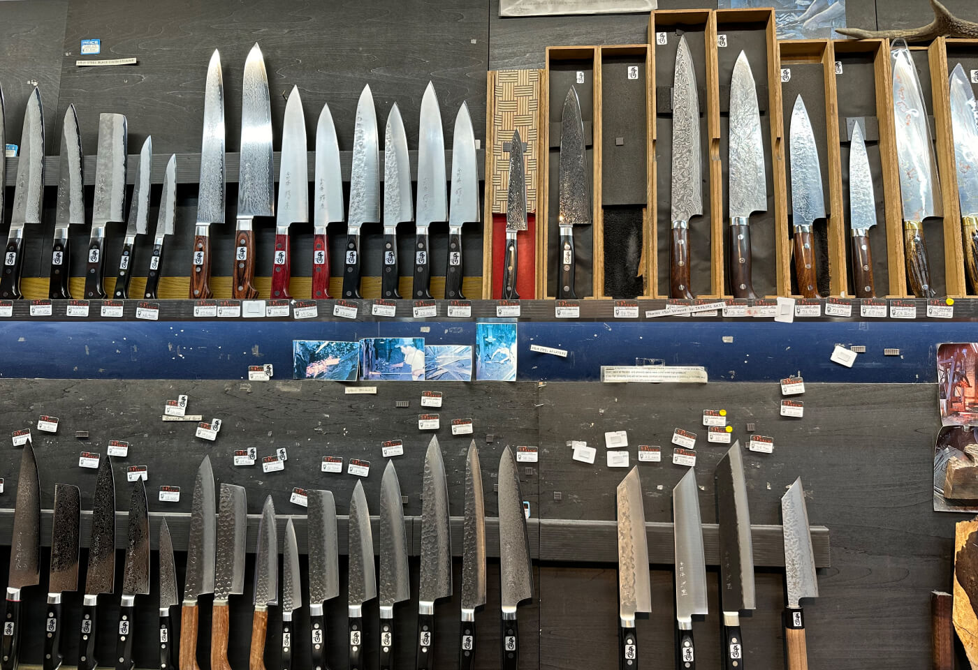 Två rader med fina japanska knivar i olika storlekar och stilar.